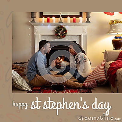 Composition of st stephen's day text and biracial couple at christmas by fireplace Stock Photo