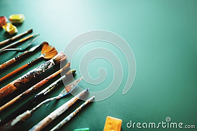 Composition of various brushes, palette knife and watercolor paints on a green background. Space for text Stock Photo