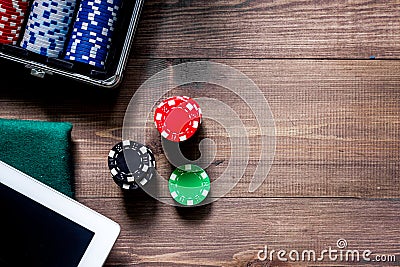 Compulsive gambling. Poker chips and the dice nearby tablet on wooden table top view copyspace Stock Photo