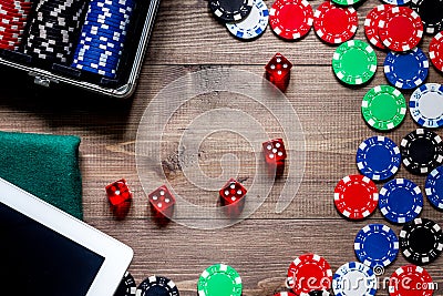 Compulsive gambling. Poker chips and the dice nearby tablet on wooden table top view copyspace Stock Photo