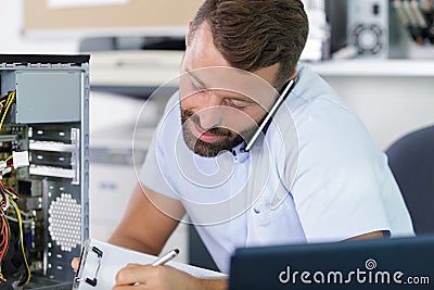 Computer engineer on phone repairing broken desktop Stock Photo