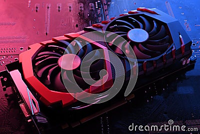 Computer game graphics card, videocard with two coolers on circuit board ,motherboard background. Close-up. With red-blue lighting Stock Photo