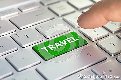 Computer keyboard with green button and word Travel. Tourist agency. Finger presses the color button on gray keyboard Stock Photo