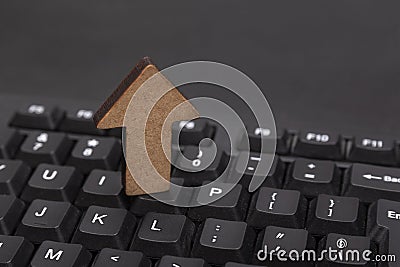 Computer keyboard and wooden up arrow. Uploading data concept Stock Photo