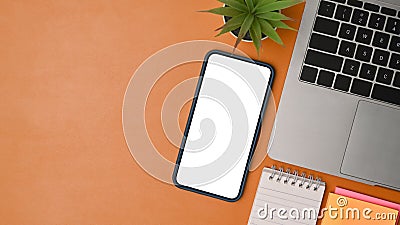 Laptop, mobile phone and notebook on brown background. Stock Photo