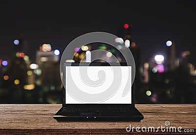 Computer laptop on wooden desk with Bokeh lights of city at night background. Clipping path computer screen Stock Photo