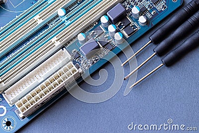 Computer motherboard and three small screwdrivers on a gray paper background. Computer equipment repair, assembly and upgrade Stock Photo