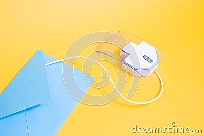 computer mouse made of transparent plastic and paper blue envelope on a yellow background Stock Photo