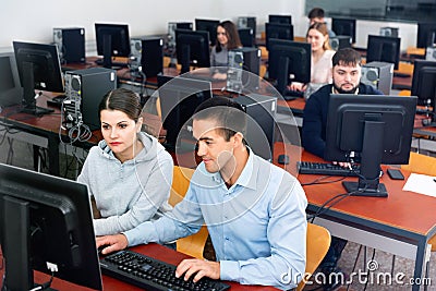 Computer science teacher supervises the execution of a programming task in a computer class Stock Photo