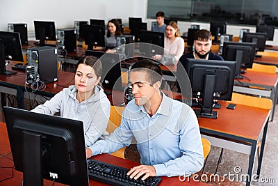 Computer science teacher supervises the execution of a programming task in a computer class Stock Photo