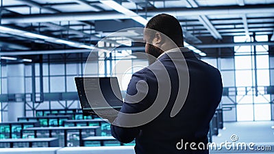 Computer scientist in server farm using laptop to patch network issues Stock Photo