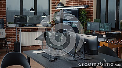 Computer screens running programming code in empty software it agency office and computers parsing data Stock Photo