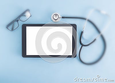 Computer tablet with a white screen on a blue background and glasses for vision, a stethoscope. The concept of selection Stock Photo