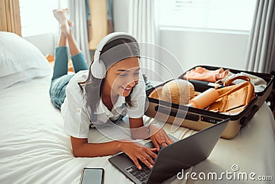 Computer travel and woman packing for a vacation with headphones typing a holiday blog. Adventure, planning and female Stock Photo