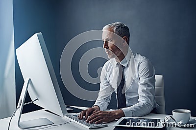 Computer, typing accountant and senior man in office, working on project online or mockup. Desktop, writing and serious Stock Photo