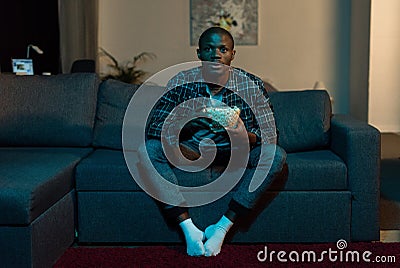 concentrated african american man with popcorn in hands watching tv Stock Photo