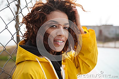 Concentrated african curly young lady wearing yellow coat Stock Photo