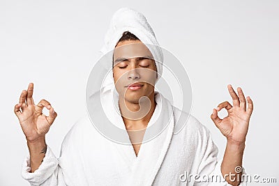Concentrated african man in lotus position cropped. Meditating with closed eyes. Male in bathrobe and towel Stock Photo
