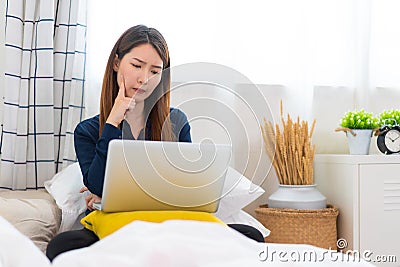 Concentrated Asian woman making decision or lack of idea working at home Stock Photo