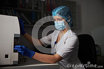 Concentrated biochemist in a face mask using a biochemical apparatus Stock Photo