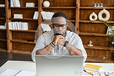 Concentrated black business man sitting in front of a laptop Stock Photo