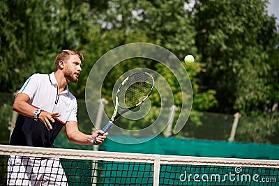 Young man in sportwear is playing tennis on out door court. Stock Photo
