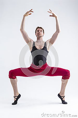 Concentrated Contemporary Ballet Dancer Flexible Athletic Man Posing in Red Tights in Ballanced Dance Pose With Hands Circled on Stock Photo