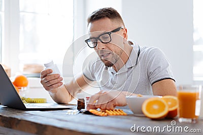 Concentrated earnest man taking biohacking supplements Stock Photo