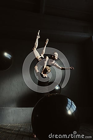 Concentrated gymnasts dancing together in the black colored studio Stock Photo