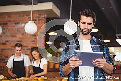 Concentrated hipster using tablet in front of working barista Stock Photo