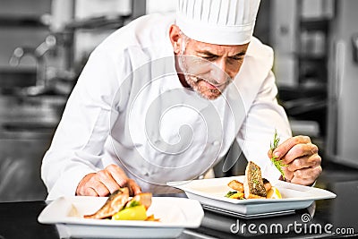 Concentrated male chef garnishing food in kitchen Stock Photo