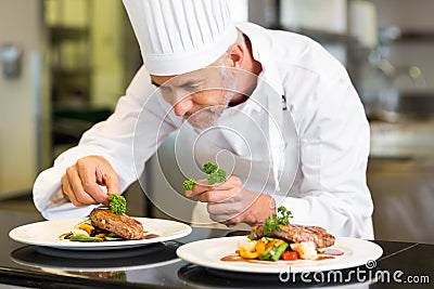 Concentrated male chef garnishing food in kitchen Stock Photo