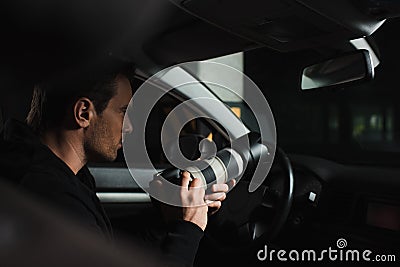 concentrated male paparazzi doing surveillance by camera with lens from Stock Photo