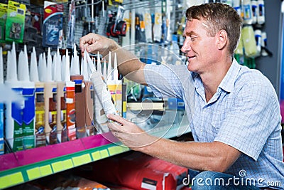Concentrated man customer choosing sealant tube in hypermarket Stock Photo