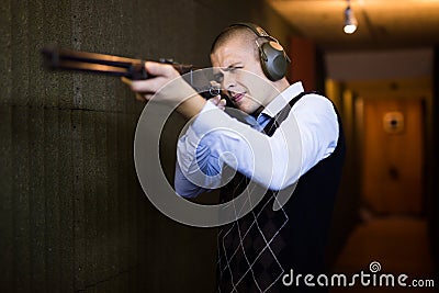 Concentrated man practicing shotgun shooting at firing range Stock Photo