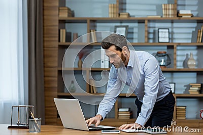 Concentrated mature male professional working in a stylish home office environment Stock Photo