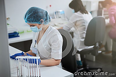 Focused biochemist in sterile latex gloves and a face mask Stock Photo