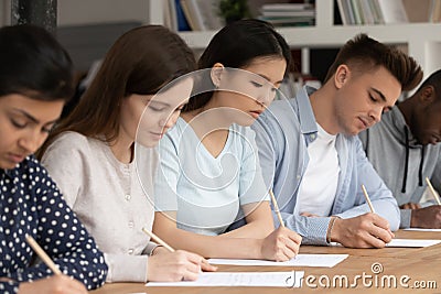 Concentrated mixed race students passing evaluation examination during session. Stock Photo