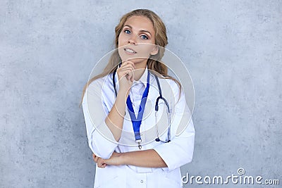 Concentrated pretty doctor with hanf on chin posing over grey background Stock Photo