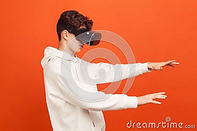 Concentrated self confident teenager in white casual hoodie moving with vr headset on eyes, online game, simulation Stock Photo