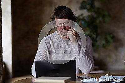 Concentrated serious young man working from home and enjoying distant job. Stock Photo