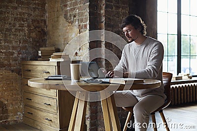 Concentrated serious young man working from home and enjoying distant job. Stock Photo