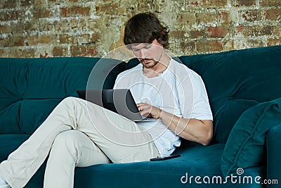 Concentrated serious young man working from home and enjoying distant job. Stock Photo