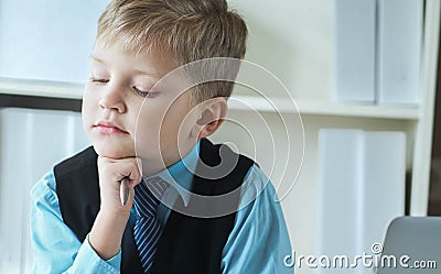 Concentrated small boy in suit thinking about money and budget increasing ways. Little financial director. Stock Photo