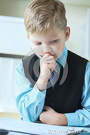 Concentrated small boy in suit thinking about money and budget increasing ways. Little financial director. Stock Photo