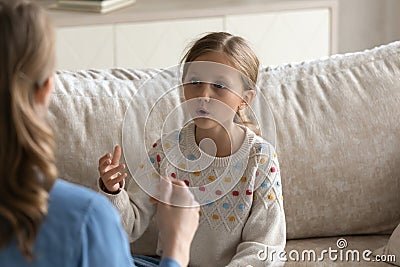 Concentrated small girl doing vocal exercises with mum and therapist. Stock Photo