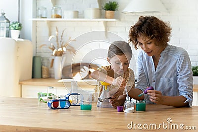 Concentrated small kid doing experiments with mum at home. Stock Photo