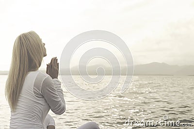 Woman prays meditating in front of a ocean view Stock Photo