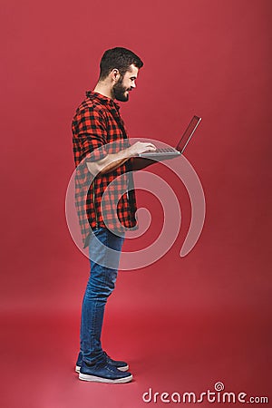 Concentrated on work. Full length portrait of a cheerful young man. Confident handsome man in casual working on laptop while Stock Photo