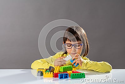 Concentrated young child playing with building blocks and career engineer Stock Photo